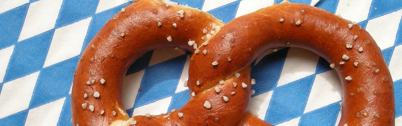 Das Bild zeigt eine Breze auf einer Tischdecke mit weiß-blauem Rautenmuster.