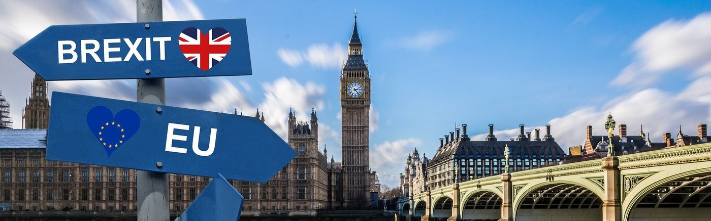 Das Bild zeigt das Parlamentsgebäude mit dem Big Ben in London. Im Vordergrund sieht man zwei Schilder mit den Aufschriften EU und Brexit. Beide zeigen in unterschiedliche Richtungen.